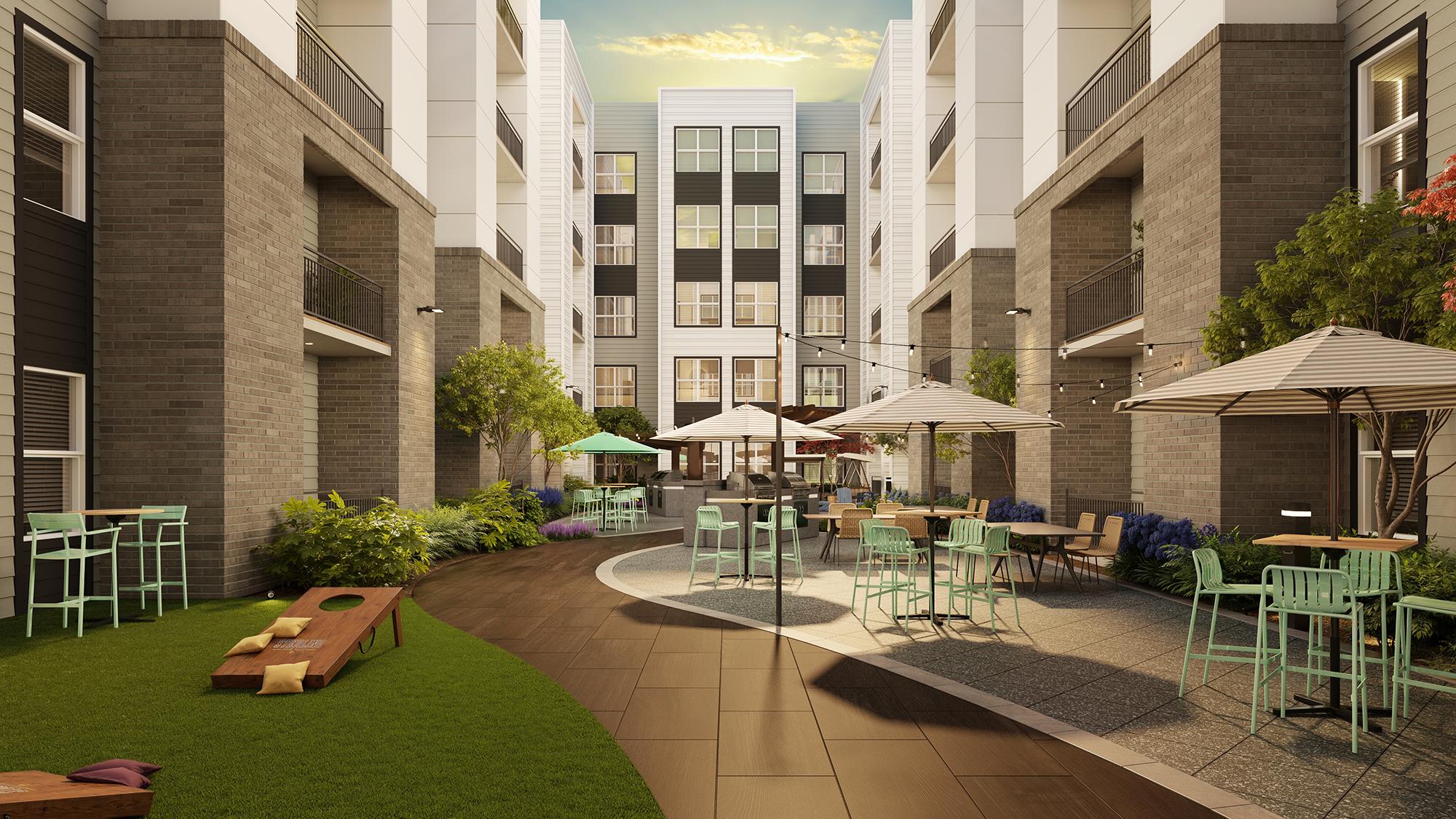 Sterling Tiger Valley Outdoor courtyard with tables, umbrellas, green chairs, and a cornhole game set between modern apartment buildings at sunset.