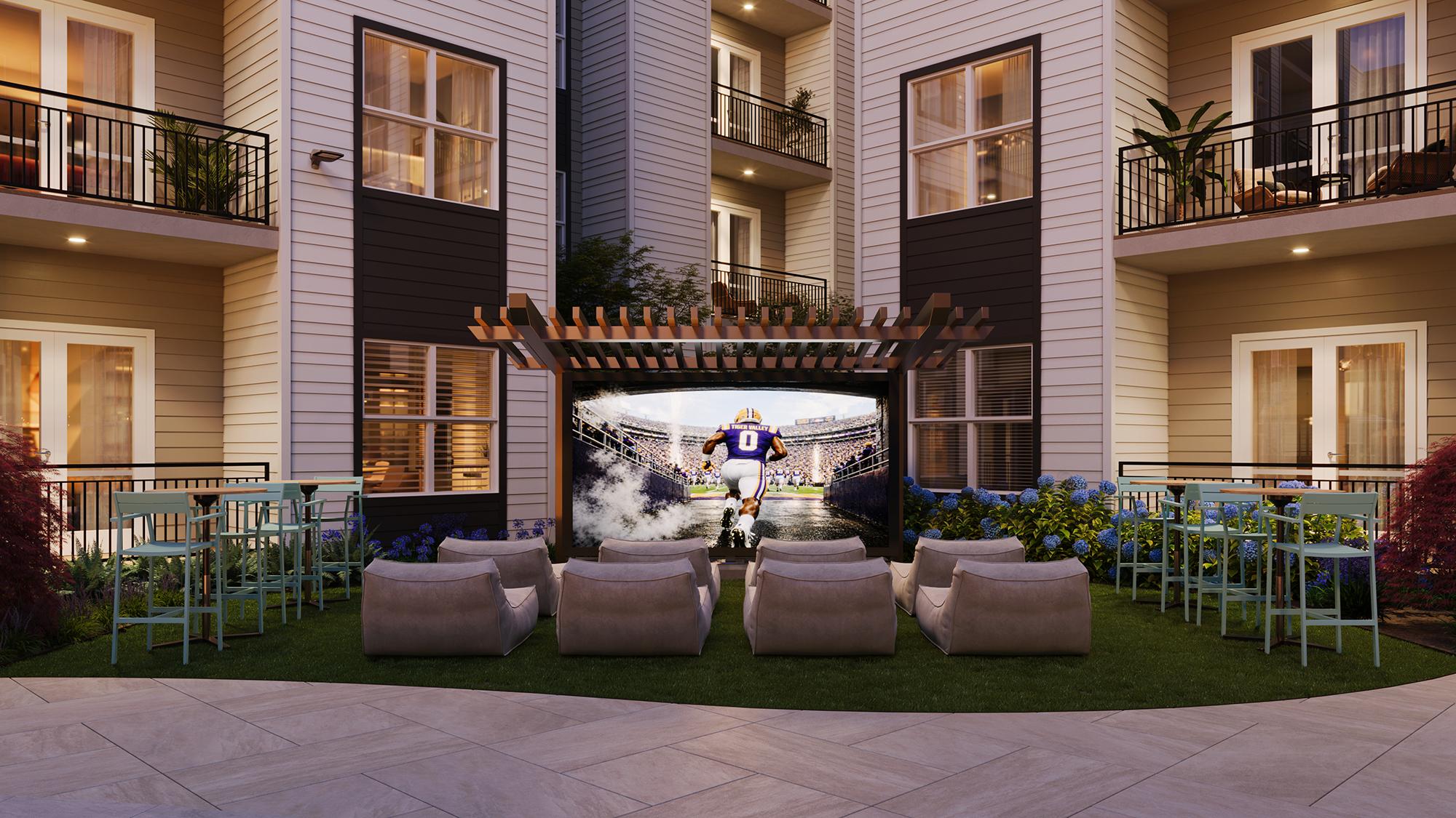 Sterling Tiger Valley Outdoor courtyard with lounge chairs facing a large screen showing a football game, surrounded by apartment balconies.