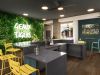 Sterling Tiger Valley Modern lounge with a plant wall, neon "Geaux Tigers" sign, yellow barstools, and a view of a pool through large windows.