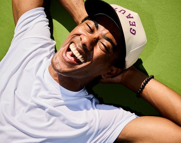 Sterling Tiger Valley A person in a white shirt and cap lies on green grass, smiling widely with hands behind their head, enjoying the sun.