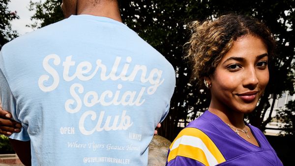 Sterling Tiger Valley A smiling woman in a purple shirt stands beside a person wearing a blue “Sterling Social Club” T-shirt.