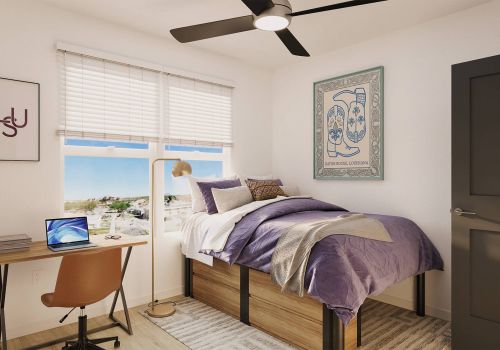 Sterling Tiger Valley A bright dorm room with a bed, desk, chair, laptop, wall art, and window with blinds letting in natural light.